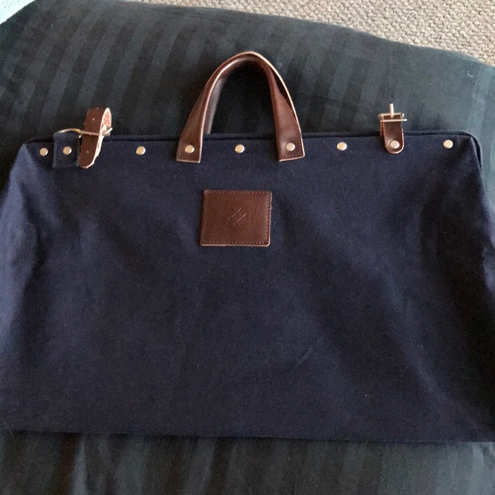 Blue canvas travel bag with brown leather straps.